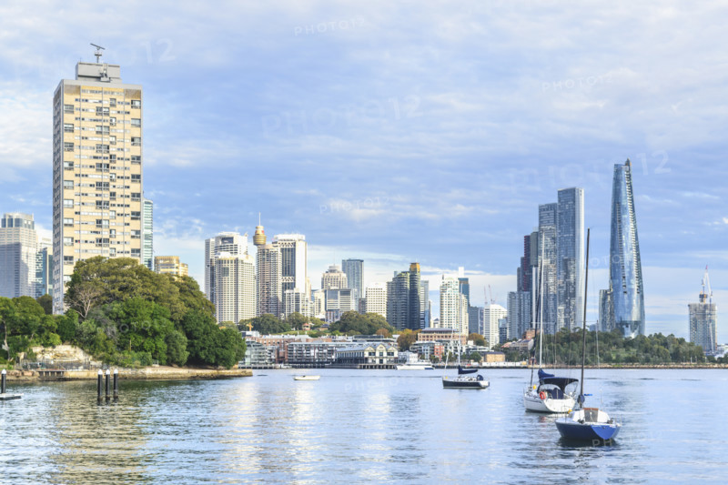 Sailboats anchored in Sydney Harbour, with skyscrapers on background