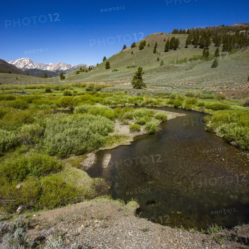 Creek flowing through valley with mountains in distance