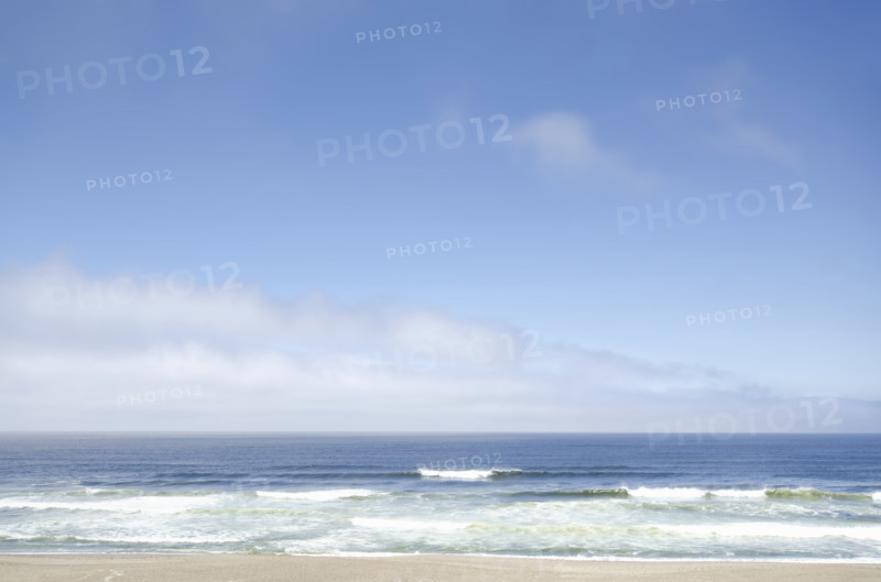White clouds and blue sky above beach and calm ocean