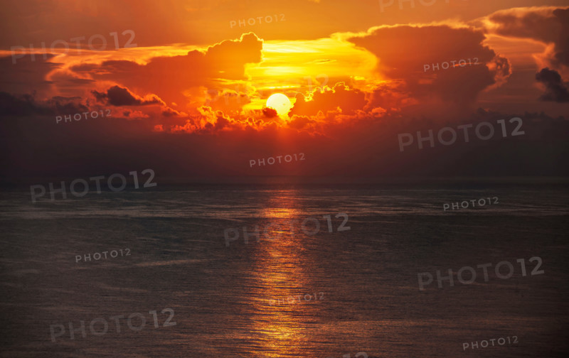 Sun rising through clouds over calm ocean. Boca Raton, Florida, United States