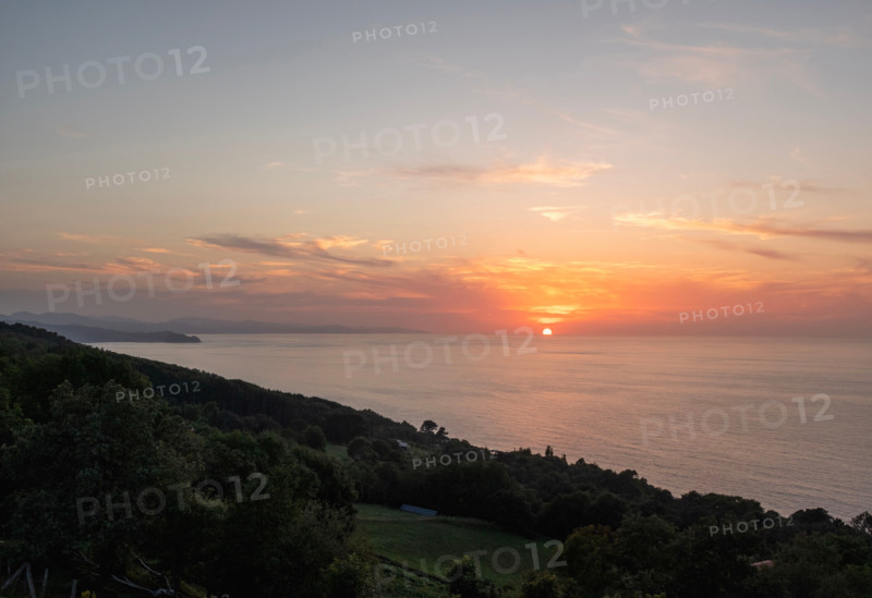 Sunset over calm sea and green hill. San Sebastian, Gipuzkoa, Spain