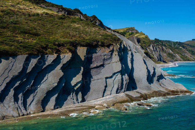 Cliffs and turquoise sea on sunny day. Zumaia, Gipuzkoa, Spain
