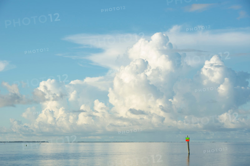 White puffy clouds over channel marker on Apalachicola Bay. Apalachicola, Florida, United States