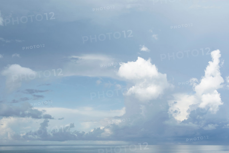 White puffy clouds over calm sea at morning. St. George Island, Florida, United States
