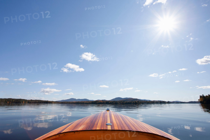 Wooden boat on calm Upper Saranac Lake on sunny day. Santa Clara, New York, United States
