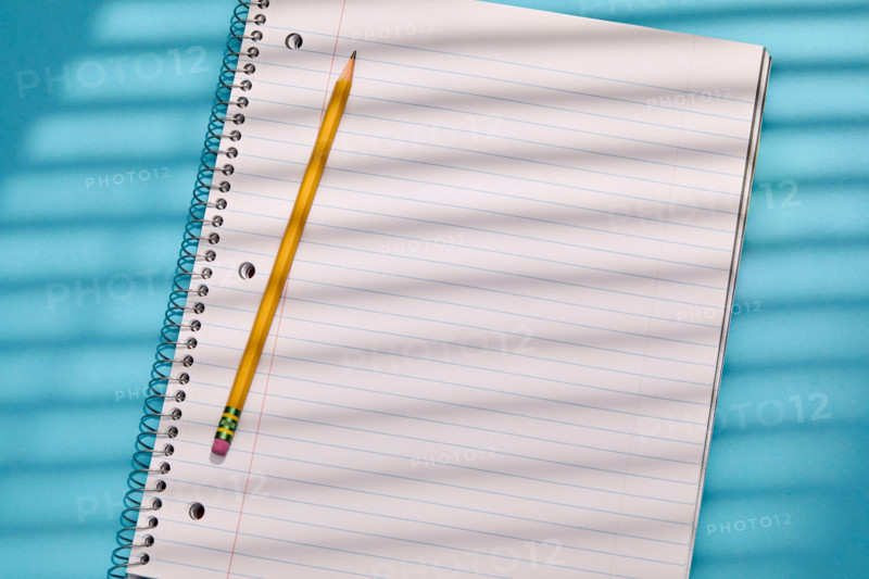 Spiral notebook and pencil on blue background. New York City, New York State, United States