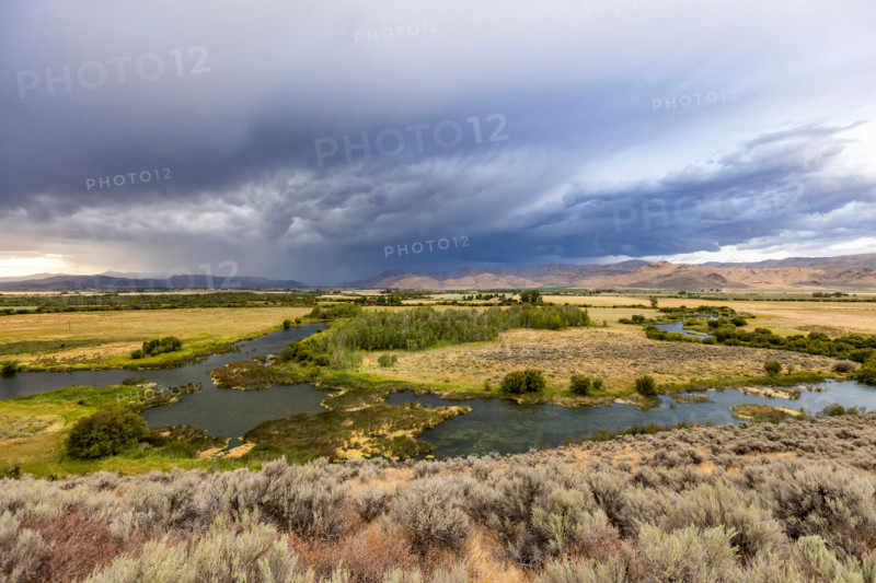 Storm clouds over fields and winding river. Bellevue, Idaho, United States
