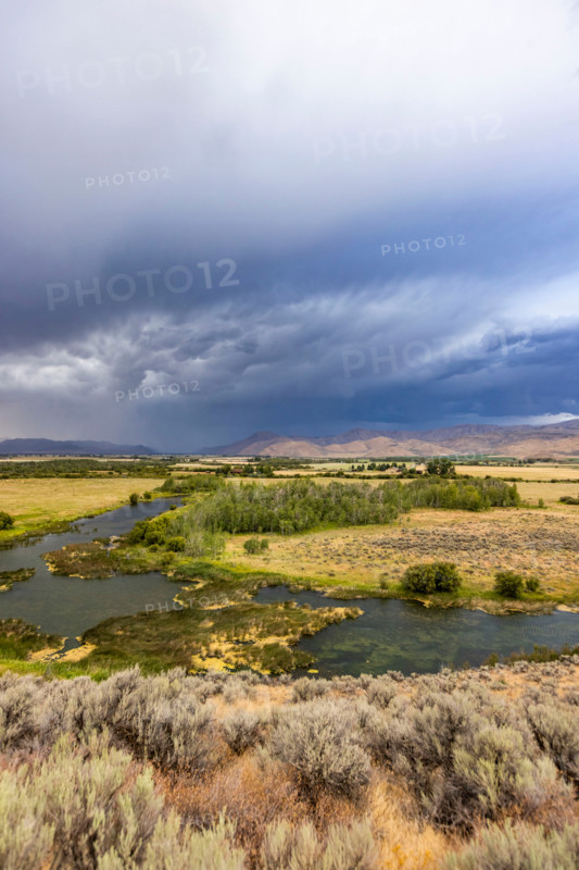 Storm clouds over fields and winding river. Bellevue, Idaho, United States