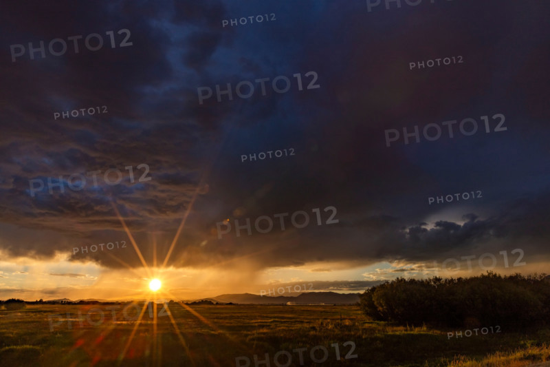 Heavy rain clouds and sun setting above landscape. Bellevue, Idaho, United States