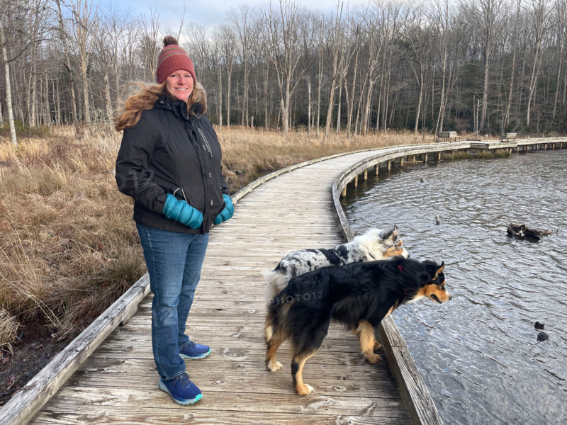 Portrait of smiling woman with two dogs by pond. Blacksburg, Virginia, United States