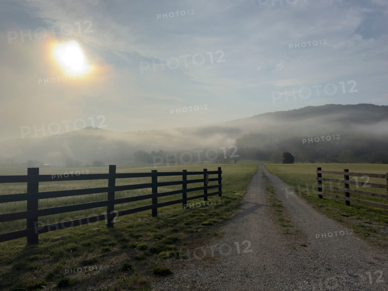 Dirt road and fields in mist at sunrise. Blacksburg, Virginia, United States