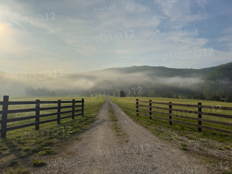 Dirt road and fields in mist at sunrise. Blacksburg, Virginia, United States