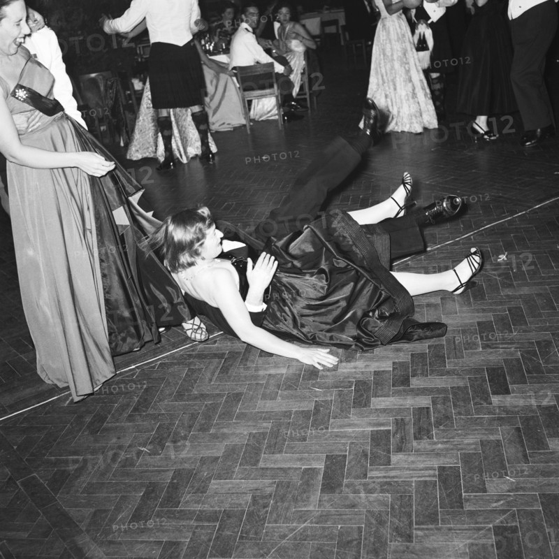 Trip, stumble and fall. A couple captured falling over on the dancefloor at the GHQ dance. The guests surrounding them are laughing. Kenya, 17 December 1954. Kenya, Eastern Africa, Africa.