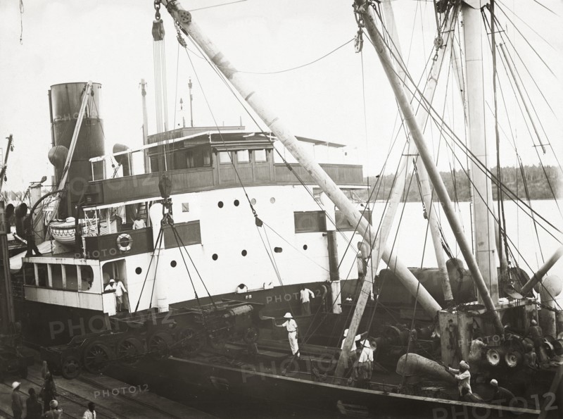 Unloading a bogie from SS Harmonides. Close up view of the cranes onboard SS Harmonides lowering a power bogie onto the dockside at Kilindini harbour. Mombasa, Kenya, circa 1926. Mombasa, Coast, Kenya, Eastern Africa, Africa.