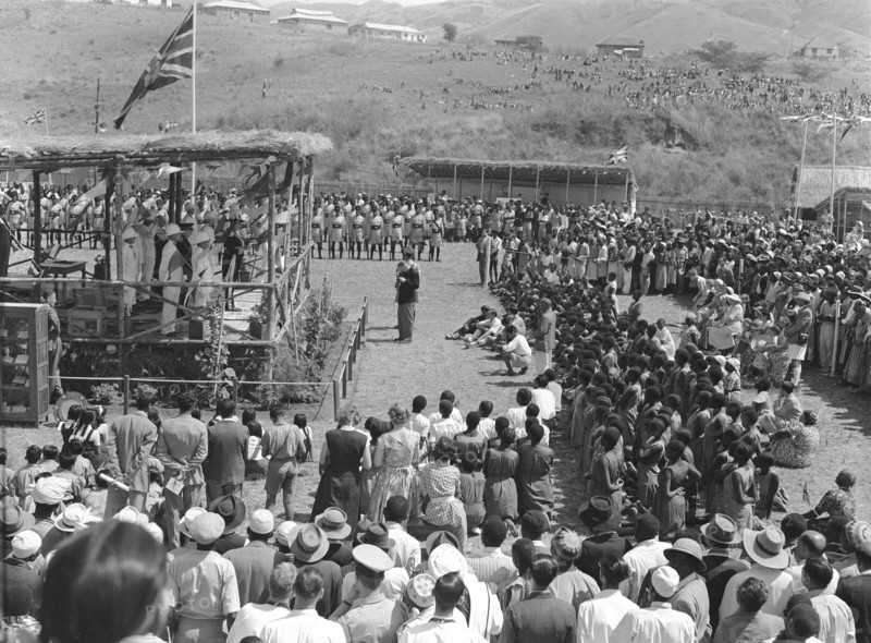 Mbeya show opening speech. A large, mixed race crowd watch the opening speech at the Mbeya show. A union jack flag flies above the speaker's podium. Mbeya, Tanganyika Territory (Tanzania), 28 August 1953. Mbeya, Mbeya, Tanzania, Eastern Africa, Africa.