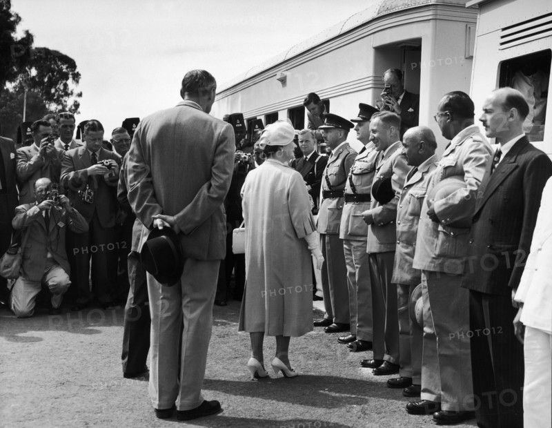 The Queen Mother visits Kenya. A publicity photograph from the East African Railways and Harbours Administration (EAR&H). Journalists take pictures of Queen Elizabeth, the Queen Mother, as she greets uniformed officials and railway staff at a stop made by the royal train on her tour of Kenya and Uganda. Kenya, February 1959. Kenya, Eastern Africa, Africa.