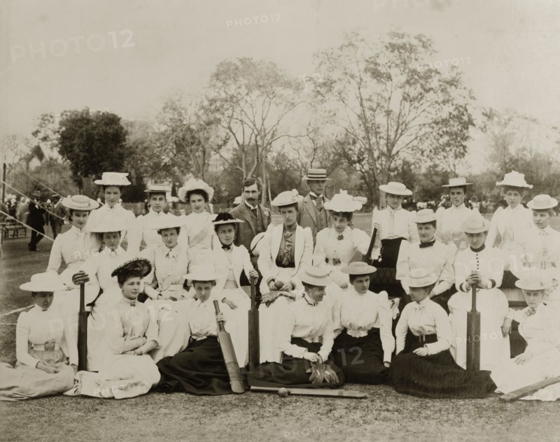 Victorian ladies' cricket. Two ladies' cricket teams in their sporting whites pose for the camera before a match. All of the women wear Victorian-style clothing including boater hats and long skirts belted tightly at the waist. Several of the group hold cricket bats. India, 1893. India, Southern Asia, Asia.