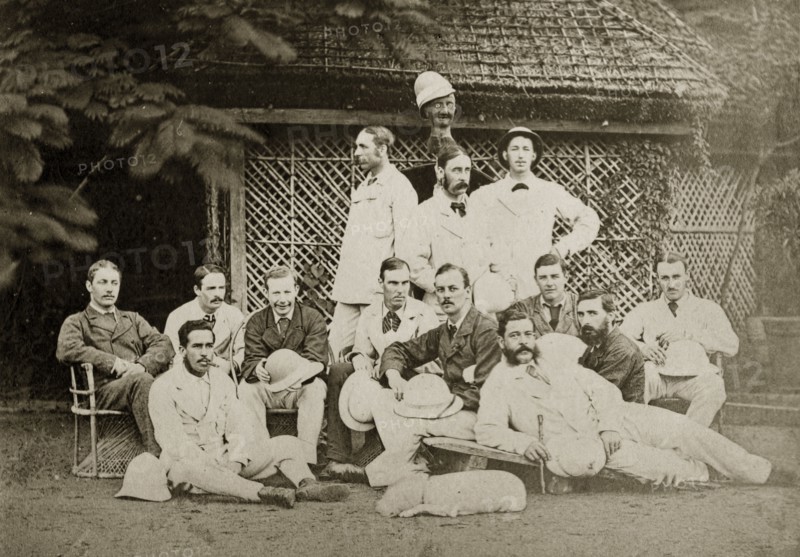 Satara and Poona cricket teams. Group portrait of the Satara and Poona cricket teams dressed in their whites. One of the players holds up a model head wearing a hat, presumbaly indicating the position of an absent team member. Bombay (Mumbai), India, circa 1875. Mumbai, Maharashtra, India, Southern Asia, Asia.