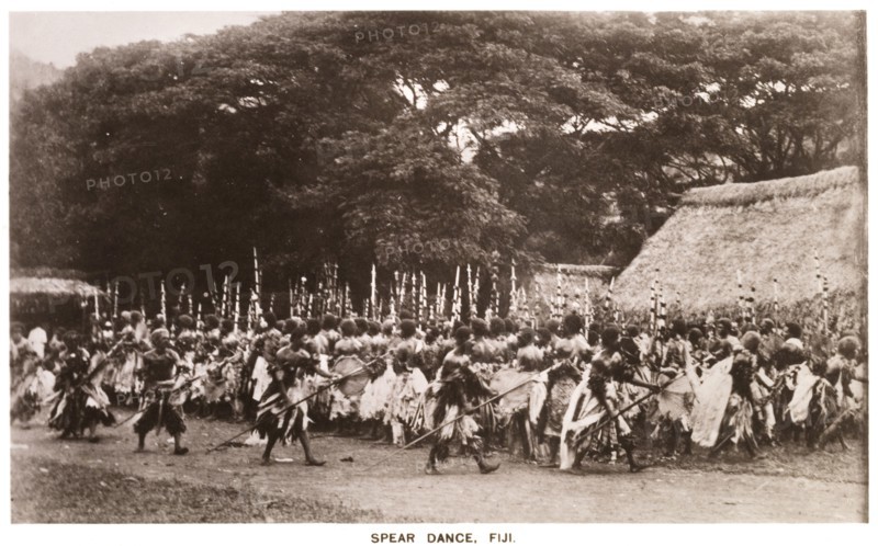 Performing a 'meke wesi'. A crowd of male Fijian dancers dressed in ceremonial costume perfom a traditional 'meke wesi' dance with spears. Fiji, circa 1920. Fiji, Pacific Ocean, Oceania.