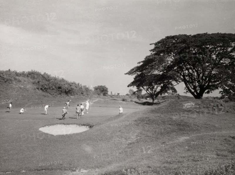 Playing golf, Rangoon. Golfers play a round on an uneven section of the golf course at Rangoon Golf Club. Rangoon (Yangon), Burma (Myanmar), circa 1952. Yangon, Yangon, Burma (Myanmar), South East Asia, Asia.