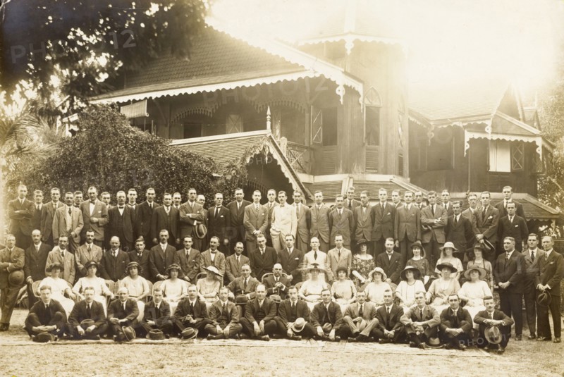 Group portrait outside a colonial house. A large number of formally dressed European men and women pose for a group portrait outside an ornate, colonial house. Probably Burma (Myanmar), 1921. Burma (Myanmar), South East Asia, Asia.
