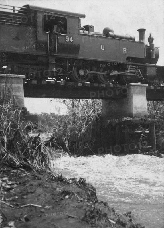 Train on washed-out bridge. A Uganda Railways locomotive pauses while crossing a damaged bridge on the Thika-Nairobi branch railway near the Fort Hall Road. Kenya, 1921., Nairobi Area, Kenya, Eastern Africa, Africa.