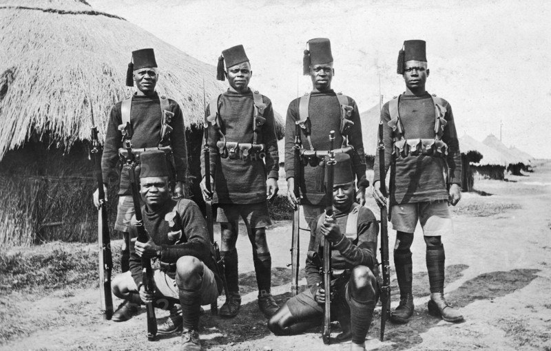 Recruits for the 2nd King's African Rifles. Six uniformed recruits in the King's African Rifles pose holding guns. British East Africa (Kenya), circa 1916. Kenya, Eastern Africa, Africa.