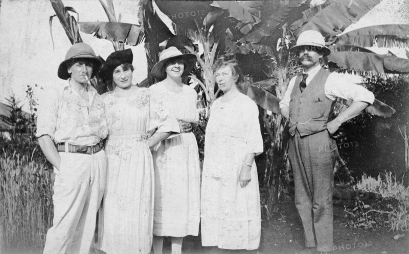The Powis family. Informal group shot of a European family standing in front of a clump of banana palms. The man on the right is identified as 'Papa Powis'. British East Africa (Kenya), circa 1920. Kenya, Eastern Africa, Africa.