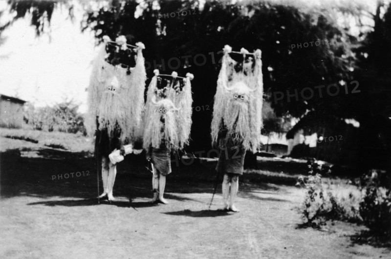 Nandi youths wearing circumcision masks. Three Nandi youths wear tall, elaborate grass headdresses and masks during their circumcision rites. Kapsabet, Kenya, February 1928. Kapsabet, Rift Valley, Kenya, Eastern Africa, Africa.