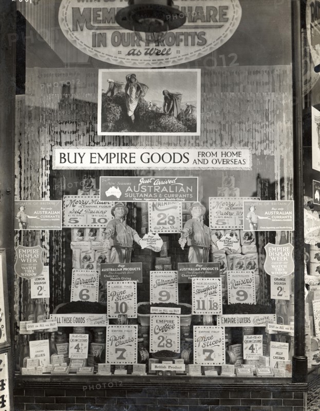 Empire goods from home and overseas. Signs in a shop window advertise a variety of Australian food products and prices. A central sign reads 'BUY EMPIRE GOODS FROM HOME AND OVERSEAS'. Location unknown, circa 1910.