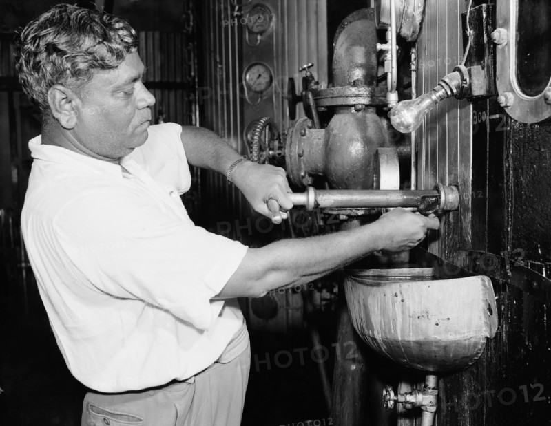 Testing samples at a sugar mill. An Indian worker tests a sample of sugar from an industrial machine covered in dials and gauges at the Miwani Sugar Mills. Miwani, Kenya, 7-8 November 1955. Miwani, Nyanza, Kenya, Eastern Africa, Africa.