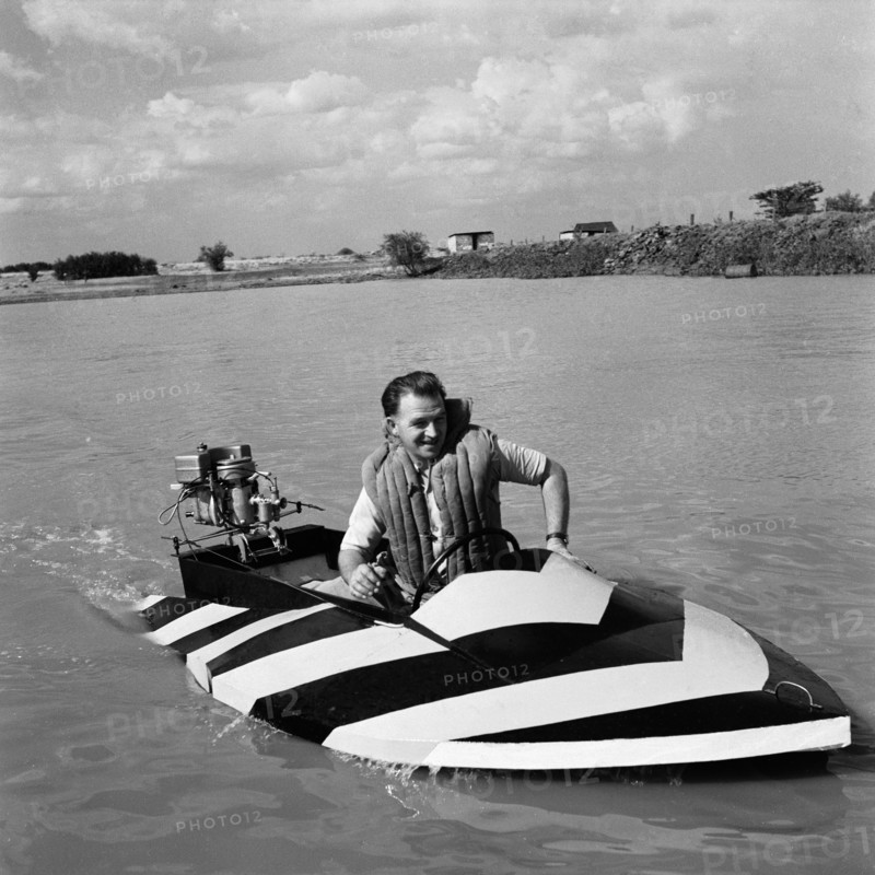 Danny Seales in a striped speedboat. Danny Seales motors across a lake in a small striped speedboat at the aquasports club meeting. Nairobi, Kenya, 14 August 1955. Nairobi, Nairobi Area, Kenya, Eastern Africa, Africa.