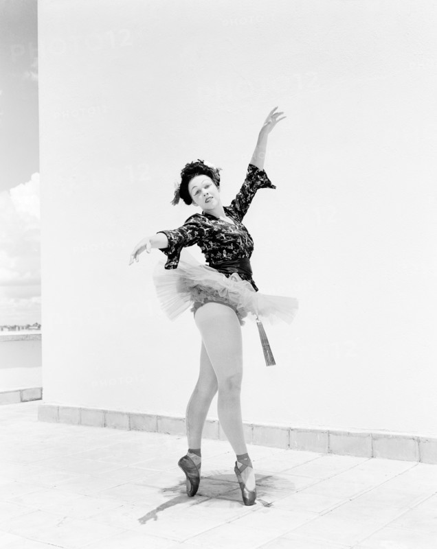 Sonja in Japanese costume. Sonja poses wearing theatrical costume comprising a tutu and ballet shoes teamed with a Japanese-style top. Her blonde hair is tucked under a dark Geisha-style wig and her oriental look is completed with theatrical make up and a decorative fan. Kenya, 4 November 1955. Kenya, Eastern Africa, Africa.