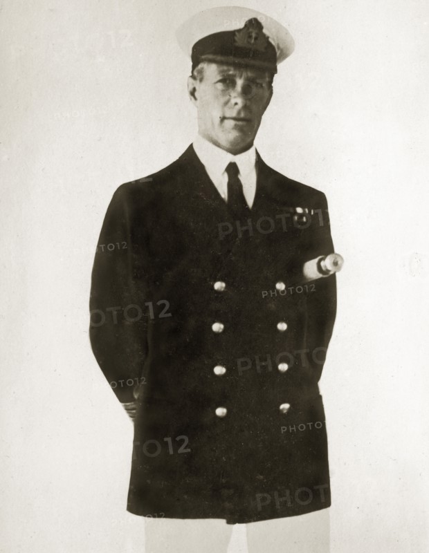 Captain Francis M Austin. Portrait of Captain Francis M Austin, commanding aboard HMS Danae, posed with a telescope tucked under his arm. Location unknown, 1923-4.