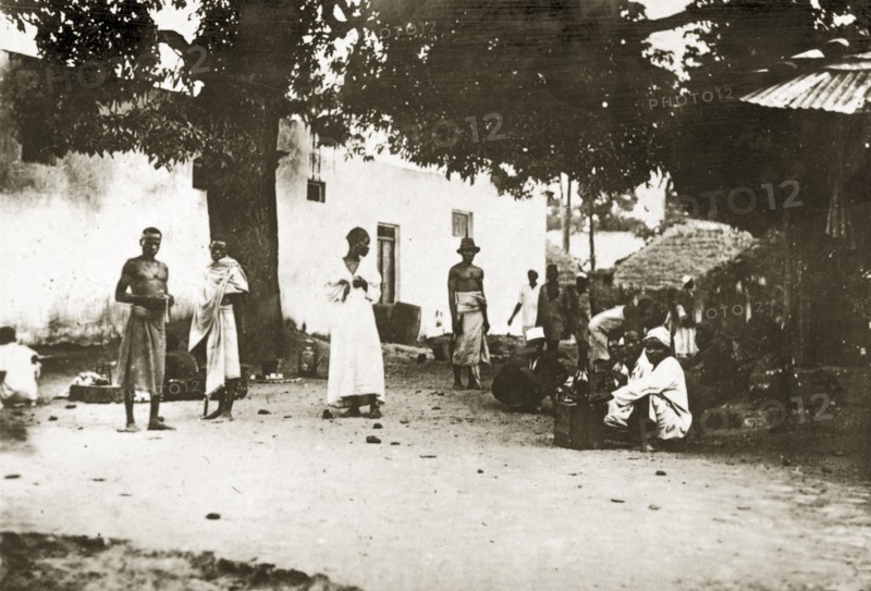Mombasan street scene. A group of people mill about on a street corner in the centre of town. Mombasa, Kenya, 12-17 January 1924. Mombasa, Coast, Kenya, Eastern Africa, Africa.