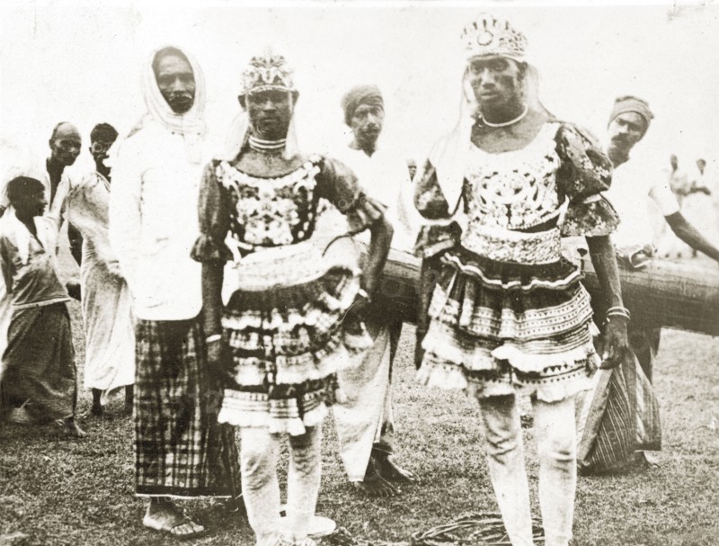 Ceylonian dancers. Two Ceylonian men dressed in traditional dance costumes wear ornate headdresses and patterned tunics heavily decorated with frills and puffed sleeves. Trincomali, Ceylon (Sri Lanka), 27-31 January 1924. Trincomali, East (Sri Lanka), Sri Lanka, Southern Asia, Asia.