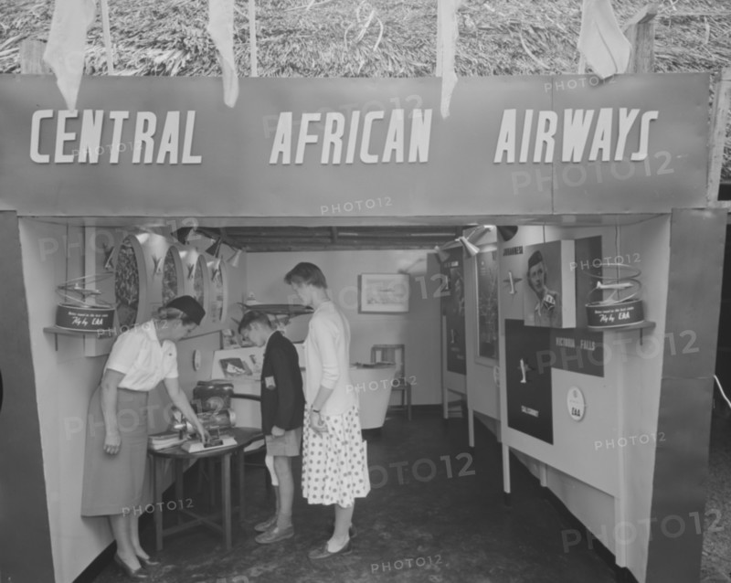 Central African Airways at the Royal Show. A woman dressed in a flight attendant's uniform shows visitors around the Central African Airways display stand at the Royal Show. Kenya, 17-20 October 1956. Kenya, Eastern Africa, Africa.