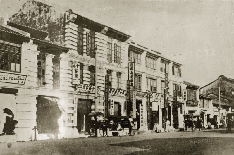 Chinese quarter in Penang. Street scene in the Chinese quarter of town. Rickshaw pullers work the street in front of a row of shops displaying signs written in Chinese script. Penang, British Malaya (Malaysia), 4-8 February 1924., Penang, Malaysia, South East Asia, Asia.
