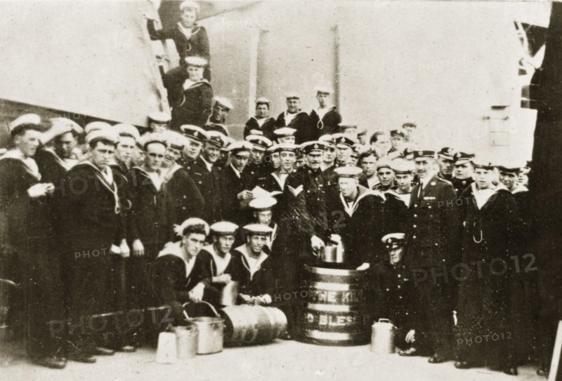 Barrel of rum. Uniformed naval personnel aboard HMS Repulse pose for a group portrait around a large barrel of rum decorated with the words 'THE KING, GOD BLESS'. Pacific Ocean between Hobart and Sydney, 4-8 April 1924., Tasmania, Australia, Australia, Oceania.