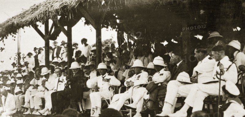 Naval officers watch a 'meke' dance. Admiral Field and other uniformed naval officers make up an audience for a 'meke', a kind of Fijian spiritual folk dance in which dancers' bodies are said to be possessed by spirits. Fiji, 21-27 May 1924. Fiji, Pacific Ocean, Oceania.