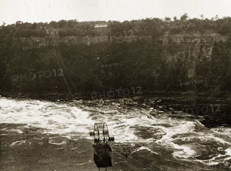 Aerial tram over Niagara Falls. An aerial tram travels on wires over the river beneath the Niagara Falls. Niagara, United States of America, 31 July-4 August 1924. Niagara Falls, New York, United States of America, North America, North America .