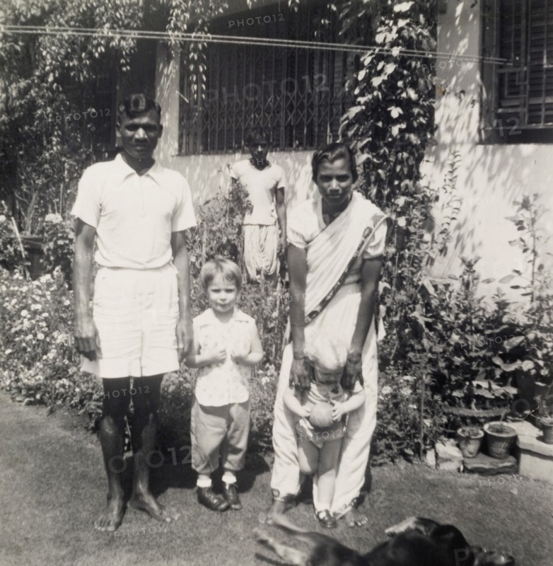 A colonial garden, India. An Indian servant and an ayah (nursemaid) entertain two young British children in the garden of a colonial house. Calcutta (Kolkata), India, circa 1954. Kolkata, West Bengal, India, Southern Asia, Asia.
