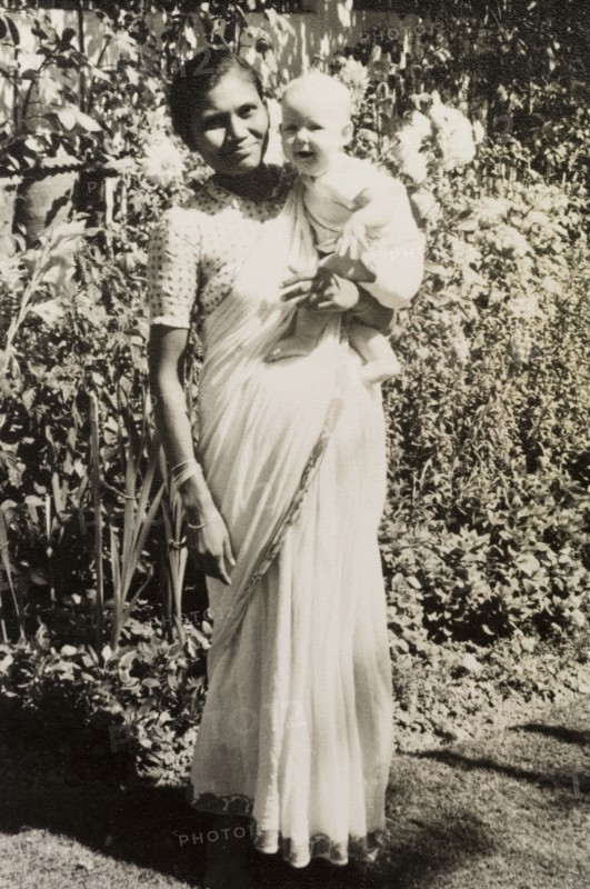 An Indian ayah poses with infant. Dressed in a flowing sari, an Indian ayah (nursemaid) identified as 'Asha' holds up a smiling British baby for the camera. Calcutta (Kolkata), India, circa 1954. Kolkata, West Bengal, India, Southern Asia, Asia.