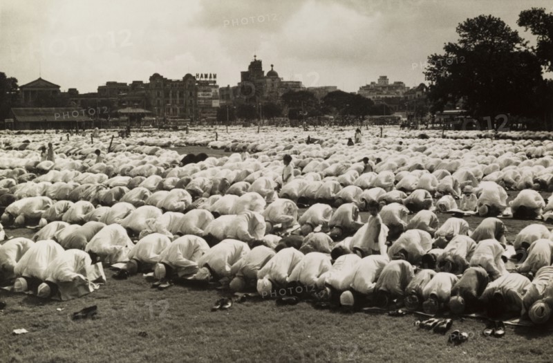 Kneeling in prayer for Eid. Hundreds of Muslim men, their shoes removed, kneel on prayer mats as they bow their heads in prayer during the Islamic festival of Eid. Calcutta (Kolkata), India, circa 1954. Kolkata, West Bengal, India, Southern Asia, Asia.