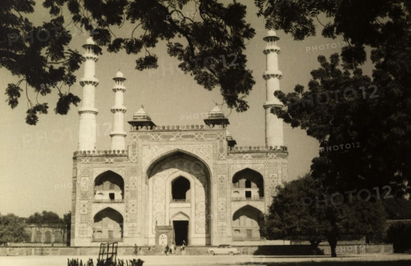Gateway to Mughal Emperor Akbar's Tomb. The marble gateway to Mughal Emperor Akbar's Tomb, featuring arched doorways and minarets, is partially obscured by the shadow of a tree. Sikandra, United Provinces (Uttar Pradesh), India, circa 1954. Sikandra, Uttar Pradesh, India, Southern Asia, Asia.