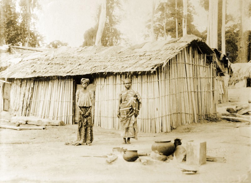Traditional bush hut, Gold Coast. A traditional bush hut with occupants standing outside. Accra, Gold Coast (Ghana), 1918. Accra, East (Ghana), Ghana, Western Africa, Africa.
