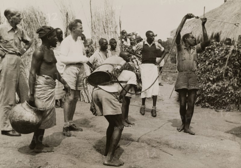 Spraying pesticide at a Congolese village. A team of men use a portable atomiser to spray vegetation with pesticide on the outskirts of a Congolese village. Belgian Congo (Democratic Republic of Congo), 1950. Congo, Democratic Republic of, Central Africa, Africa.