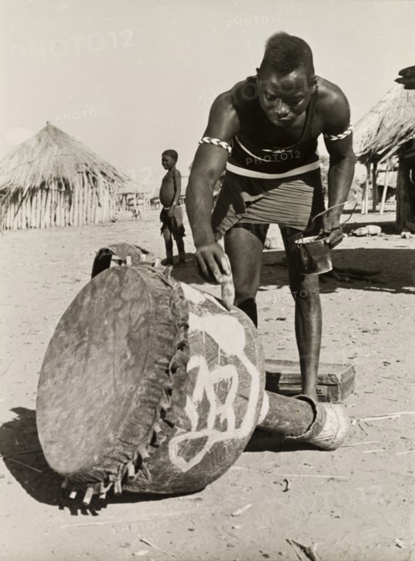 Painting a djembe drum. A Tonga (Batonga) man in traditional dress paints a decorative pattern onto a djembe drum. Probably Southern Rhodesia (Zimbabwe), circa 1955. Zimbabwe, Southern Africa, Africa.