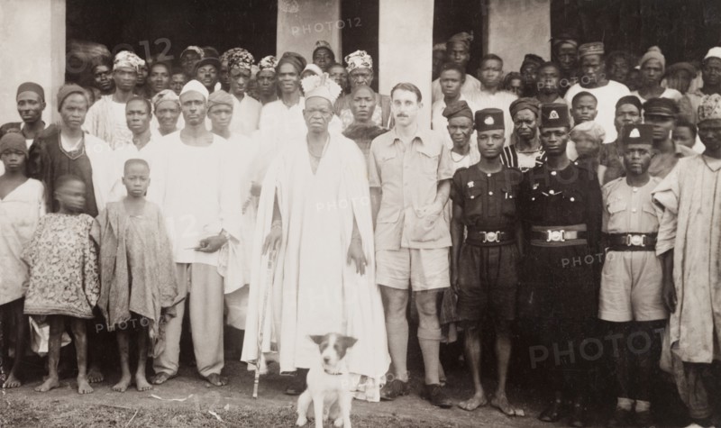 Cyril Iles with a Nigerian chief. British colonial officer, Cyril Iles, poses for the camera beside a Nigerian chief. The pair are surrounded by several uniformed police officers and a crowd of civilians. Probably Ikare, Nigeria, circa 1950. Ikare, Ondo, Nigeria, Western Africa, Africa.