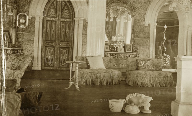 Interior at the Palace of Mysore. An opulent interior inside the Palace of Mysore. Decorated with ornate wallpaper and mirrors, the room is furnished with comfortable couches and elaborate chandeliers. Mysore, Karnataka, India, 1922. Interior of Palace at Mysore, the official residence of the former royal family. It is now one of the most famous tourist attractions in Mysore. Mysore, India, 1922. Mysore, Karnataka, India, Southern Asia, Asia.
